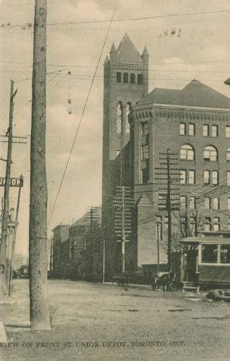 Black and white photo postcard depicting Front St. W. and Union Depot, with a streetcar and hor…