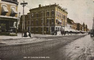 Colorized photograph of two ladies walking on the sidewalk outside of buildings lining a downto…