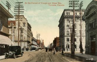 Colorized photograph of cars, buggies and people on a busy city street.