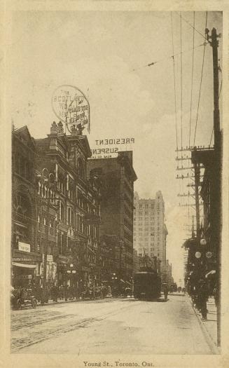 Black and white photograph of tall buildings on both sides of a city street.