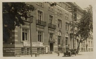 Black and white photograph of a large, five story, brick commercial building.