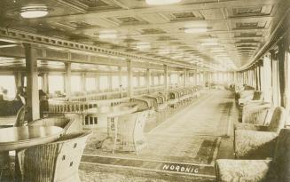 Sepia-toned photo postcard depicting the passenger lounge inside the steamship Noronic. The bac…