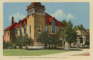 Picture of large town hall with a tower and small library building to the right. 