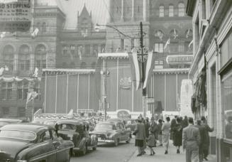 A photograph of a city hall decorated in bunting and flags of the United Kingdom, with a stage …