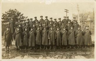 Black and white photograph of three rows of servicemen posing for a portrait in the mud and sno…