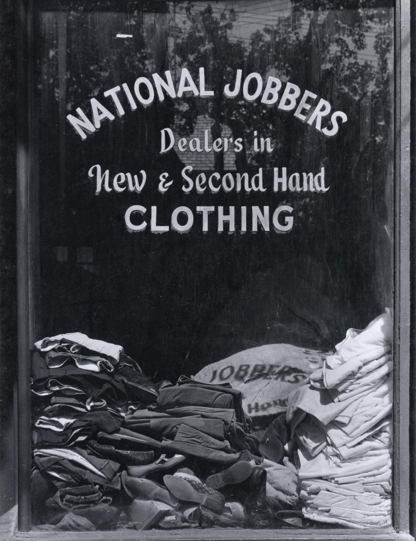 A photograph of a store window, with the words "NATIONAL JOBBERS / Dealers in / New & Second Ha…