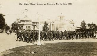 Black and white picture of soldiers standing in front of dozens of tents.