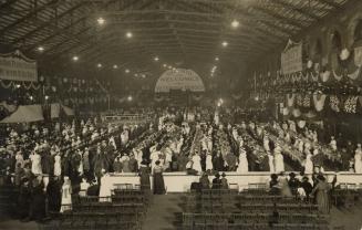 Black and white picture of soldiers sitting in rows of long dining tables. Waitresses in white  ...