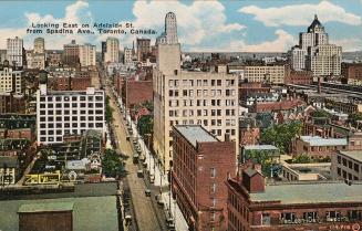 Color, aerial shot of tall skyscrapers on either side a busy street of a city down town.