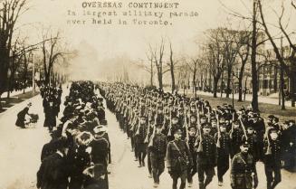 Black and white picture of soldiers marching on an icy city street while crowds of civilians lo…