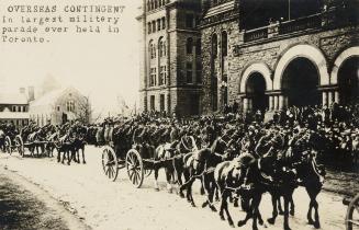 Black and white picture of soldiers riding in horse drawn carriages in front of dignitaries sta…