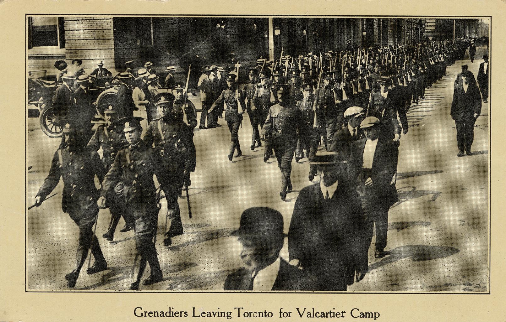 Black and white picture of soldiers marching on a city road.