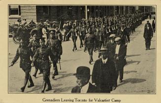 Black and white picture of soldiers marching on a city road.