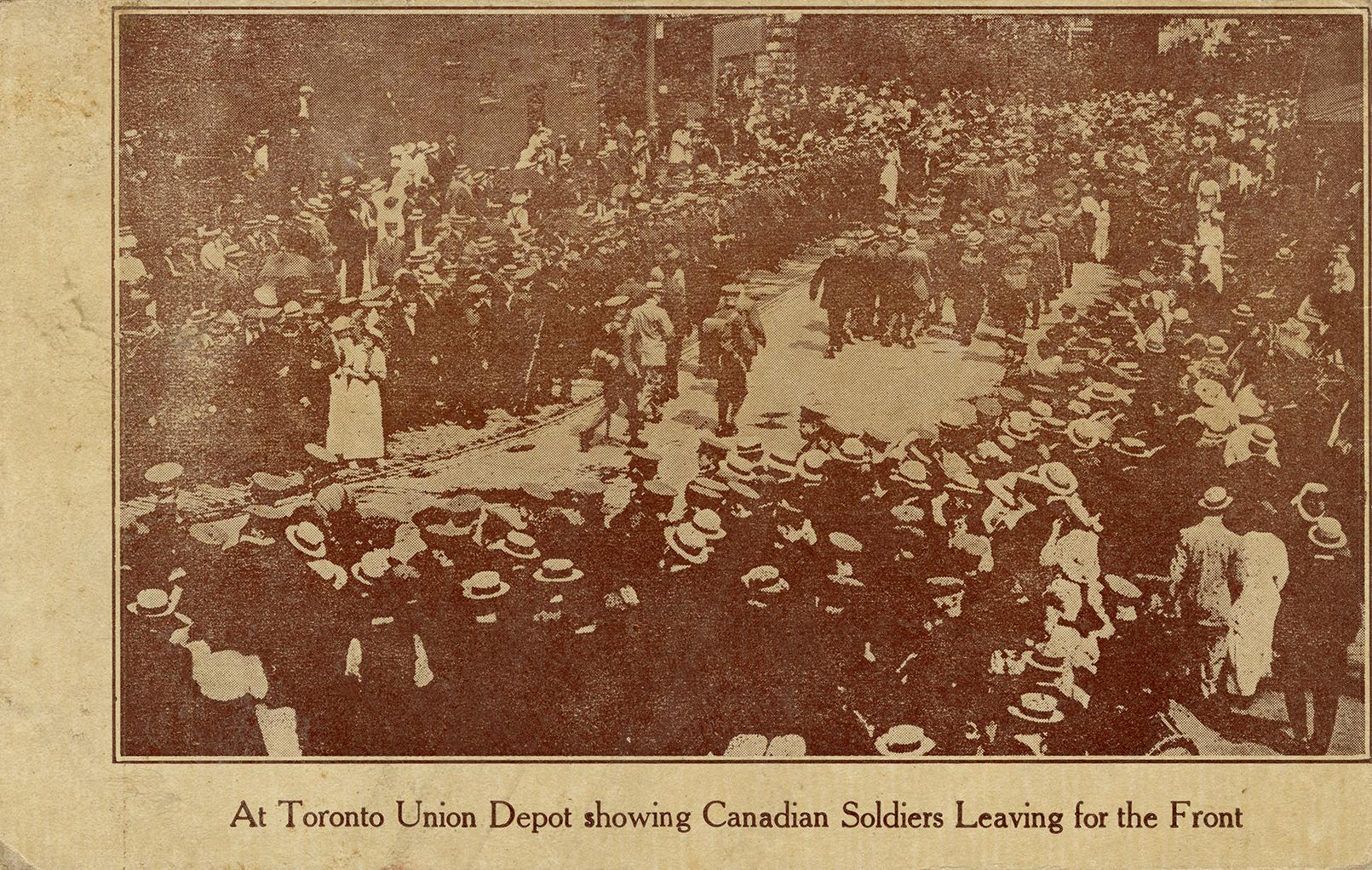 Sepia toned photograph of soldiers marching on a city road with civilian onlookers.