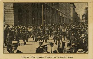 Black and white photograph of soldiers marching on a city road.