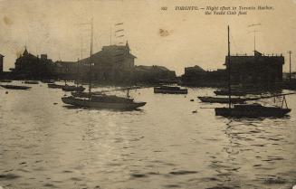 Sepia-toned photo postcard depicting the Toronto harbor with boats and yachts on the water. The…