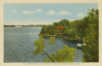 Colorized photograph of a view of a waterway, with summer homes on the river bank.