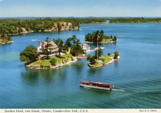 Color, aerial photograph of a view of a waterway, with a large home on an island connected by a…