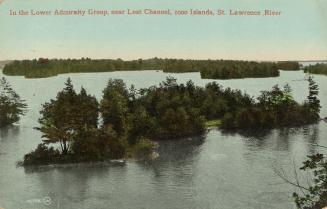 Colorized photograph of a body of water with wilderness surrounding it; forested islands in the…