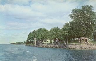 Colorized photograph of an island with a big house and boat house built on it in the middle of …