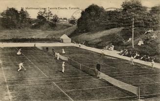 Black and white photo postcard depicting lawn tennis with several individuals playing on the co…