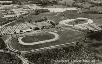 Black and white photo postcard depicting an aerial view of oval tracks. The caption on the bott…