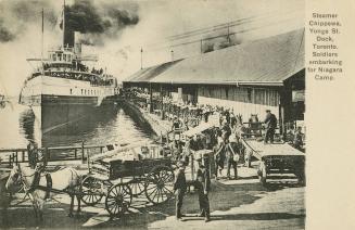 Black and white photo postcard depicting soldiers onboarding a steam ship to embark on their jo…