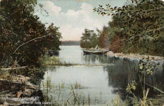 A man in a boat on a narrow portion of a river.