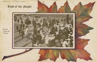 Colour photo postcard depicting depicting a crowd of pedestrians crossing over rail tracks to r…