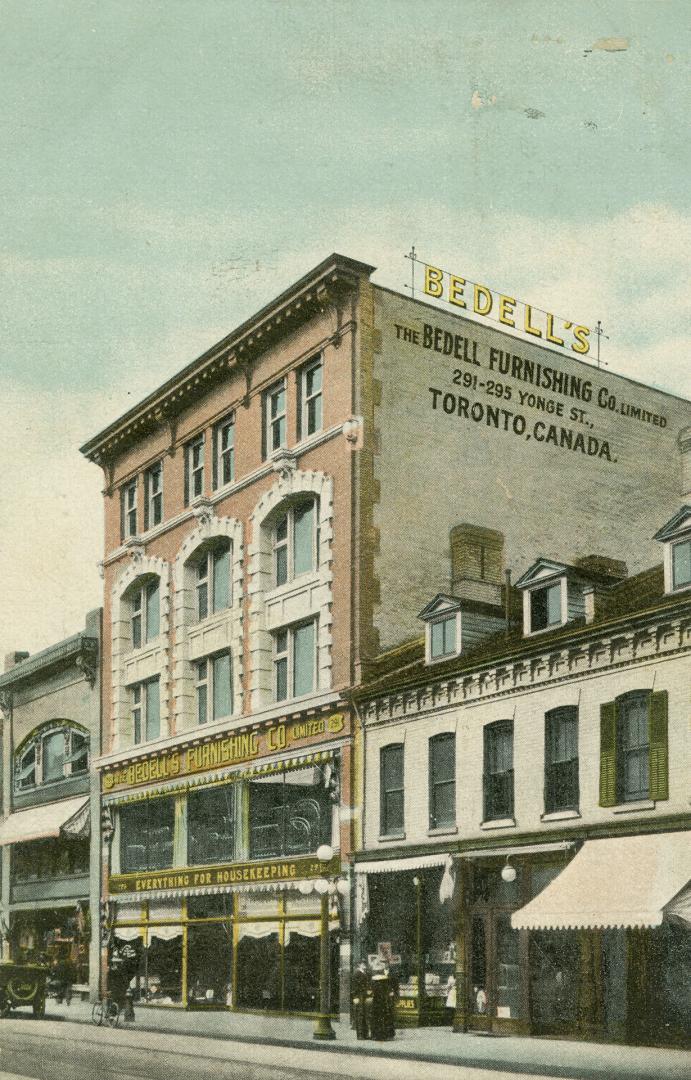 Colour postcard depicting a 4-story building with a rooftop sign "Bedell's" and the side and fr…