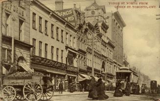 Sepia-toned photo postcard depicting a view of Yonge Street with many shops, a streetcar, and p…