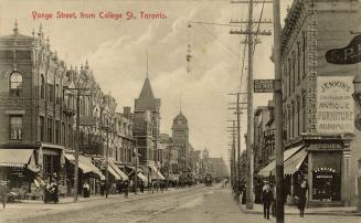 Black and white photo postcard depicting a view of Yonge Street looking south, with many shops …