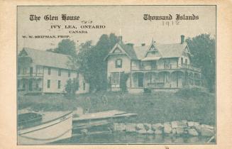 Black and white photograph of two large cottage home on the bank of a river.