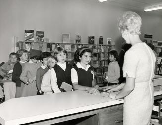 Children lined up at librarian's desk. 