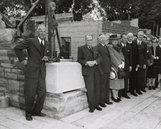 Picture of a group of people gathered at a building cornerstone saying 1947. 