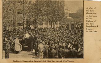 Black and white picture of a huge crowd swarming around a car in front of a warehouse type of b…