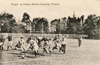 Black and white photo postcard depicting male rugby players in action. The caption at the top s…