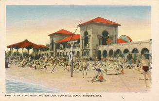 Colorized photograph of many people sitting on a beach in front of building with a long set of …