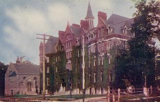 Colorized photograph of a huge, Victorian building constructed of red stone.