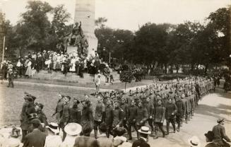 Black and white photograph of marching in front of a stone monument.