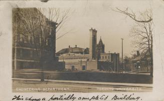 Sepia-toned photo postcard depicting a view of some buildings at a university campus. The capti…