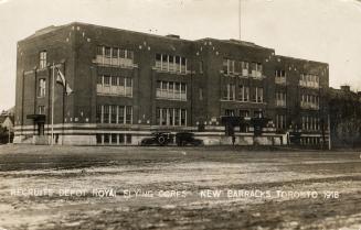 Black and white photo postcard depicting the exterior of a large three-story building. The capt…