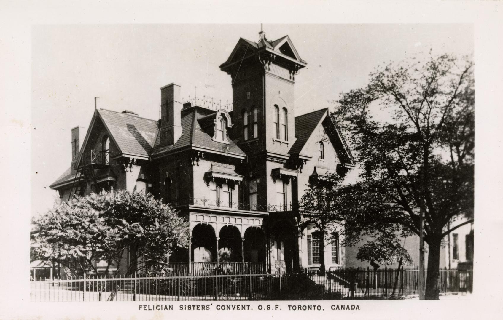 Black and white photo postcard depicting the exterior of a home with arches on its front patio …