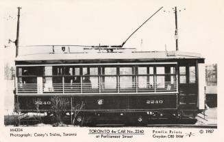 Black and white photo postcard of a streetcar with windowed sides, with the number 2240 visible…