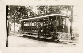 Black and white photo postcard of a streetcar with open sides, a front grill, the number 22 on …