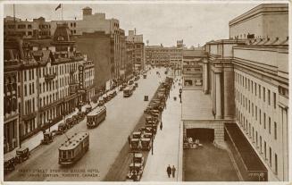 Sepia tone photograph of streetcars and other traffic on a busy city street with large building…