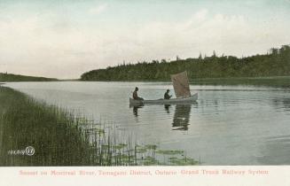 Colorized photograph of two men paddling a canoe with a sail. Water is surrounded by wilderness…