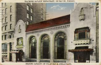 Colour photo postcard depicting the exterior frontage of a two-story building with three large …