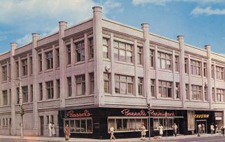 Colour photo postcard depicting the exterior frontage of a three-story building with a restaura…