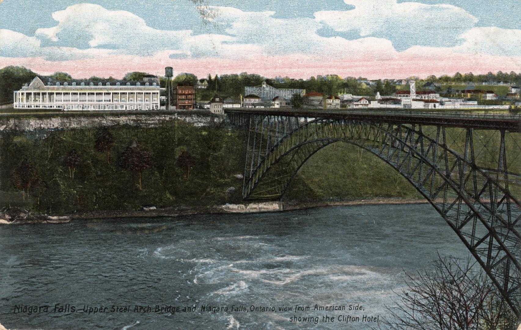 Colorized photograph of a steel bridge spanning over a river with rapids. Large, white public b…